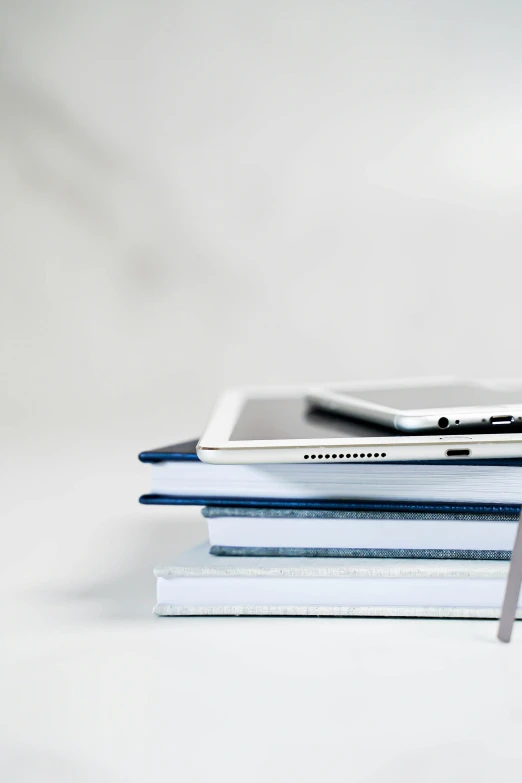 a stack of books that have a cell phone on top