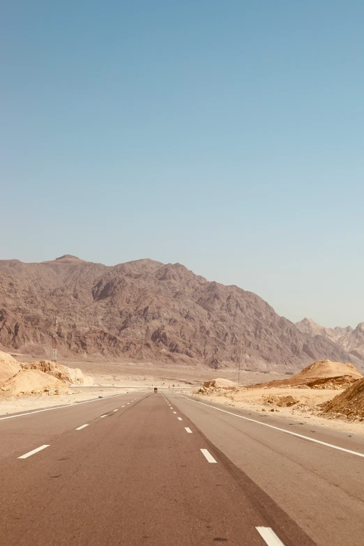 a desert road has mountains and a stop sign