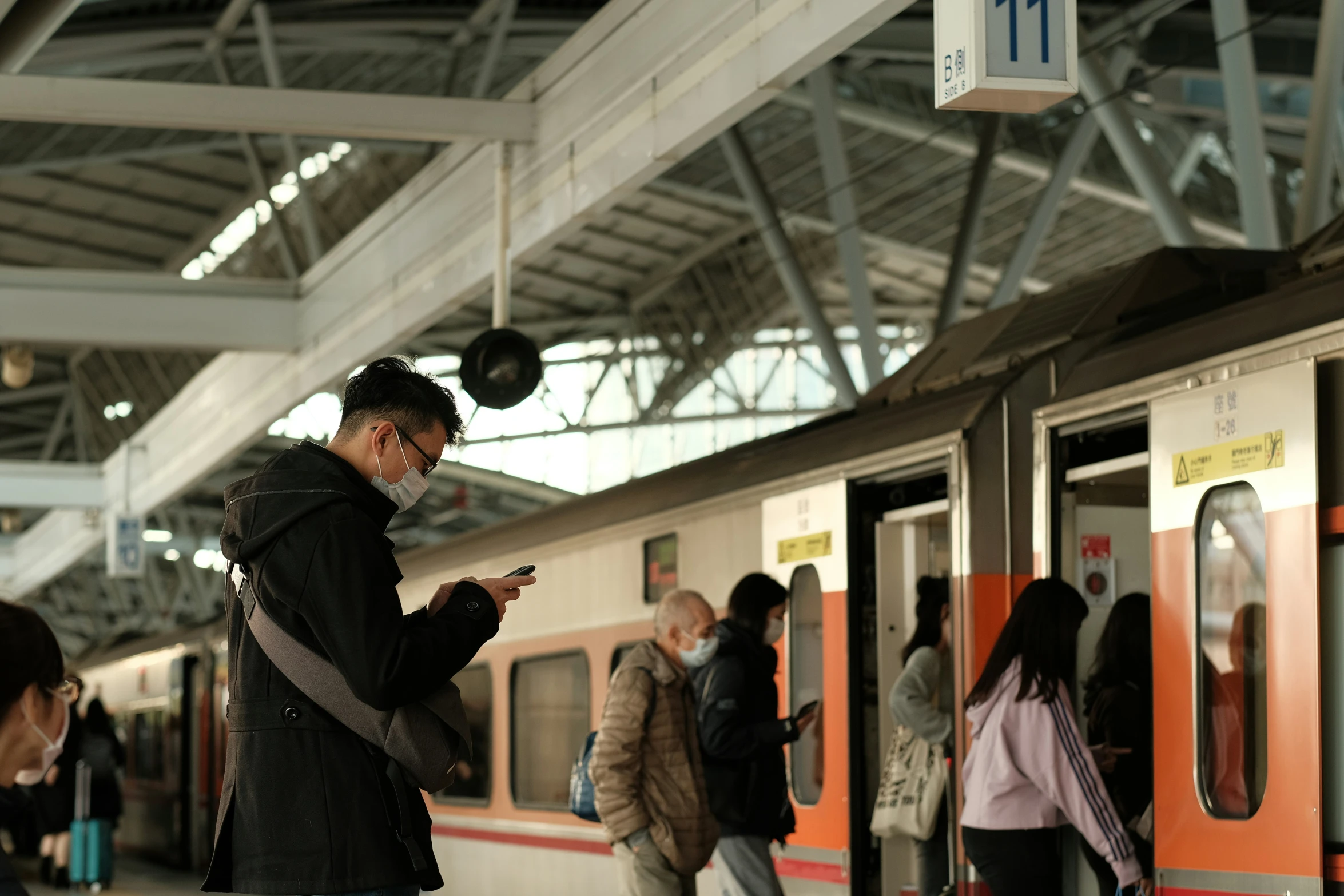 man with cell phone on commuter platform at train station