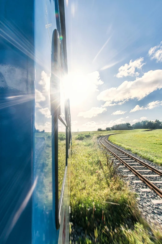 the sun shines bright from behind train tracks