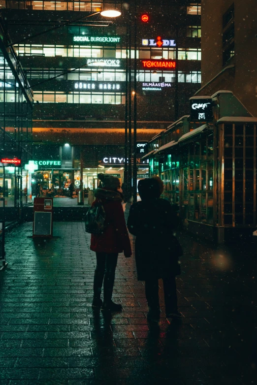 people walking and walking on the sidewalk in the rain at night