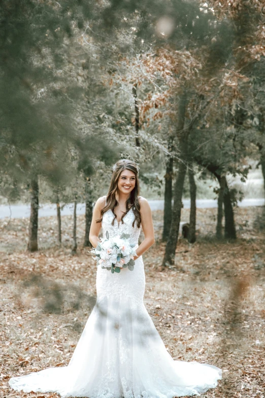 a woman standing in a field with trees