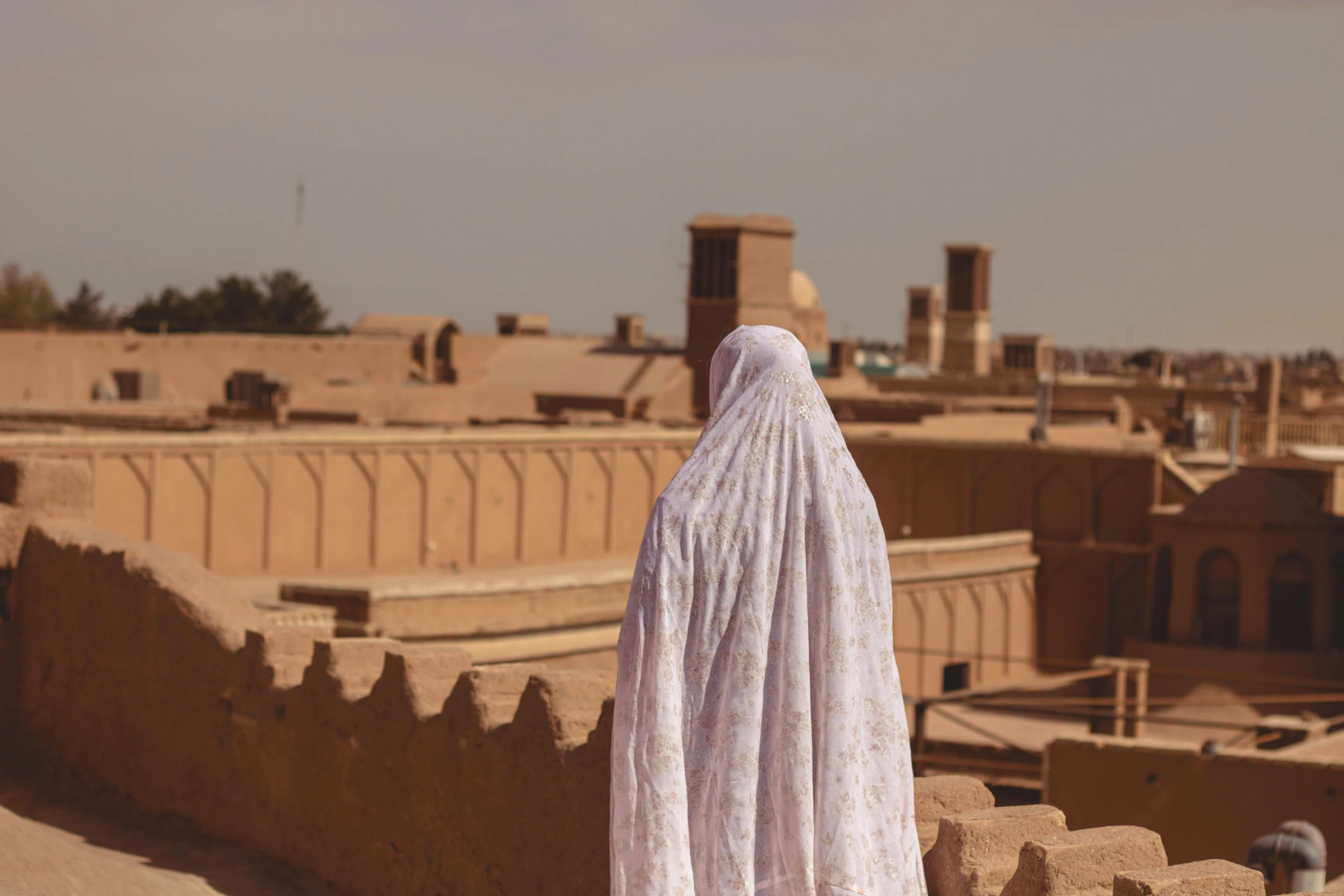 a woman standing next to a wall in a village