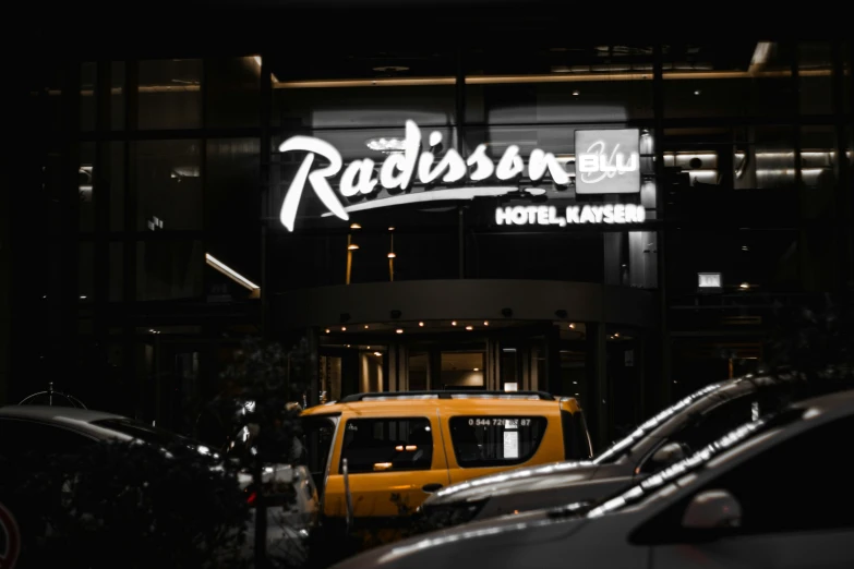 the neon sign of radissian el, with several parked cars in front of it