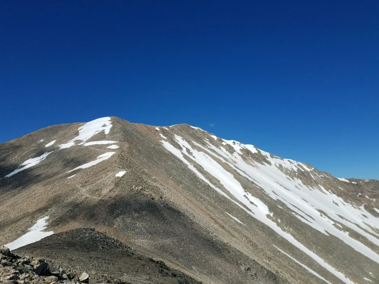 a mountain top with snowy peaks and rocks below