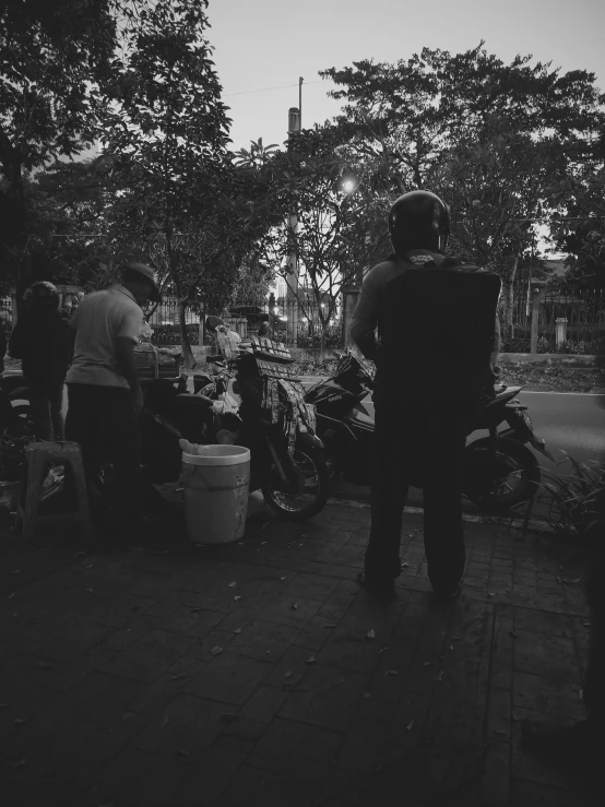 people standing on a sidewalk near parked motor bikes