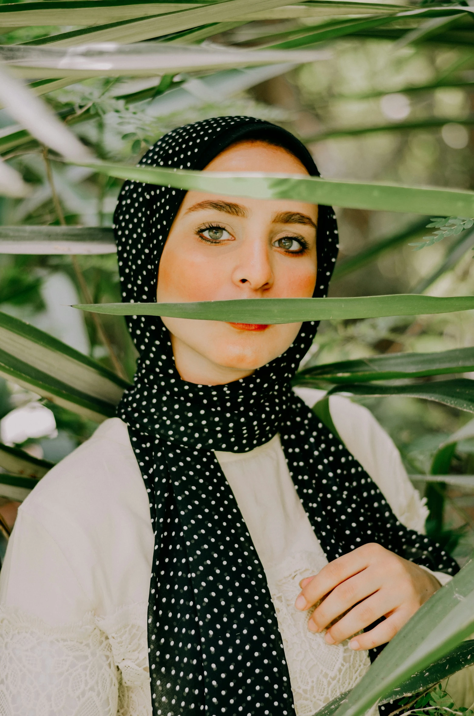 a woman is wearing a black and white scarf with polka dots