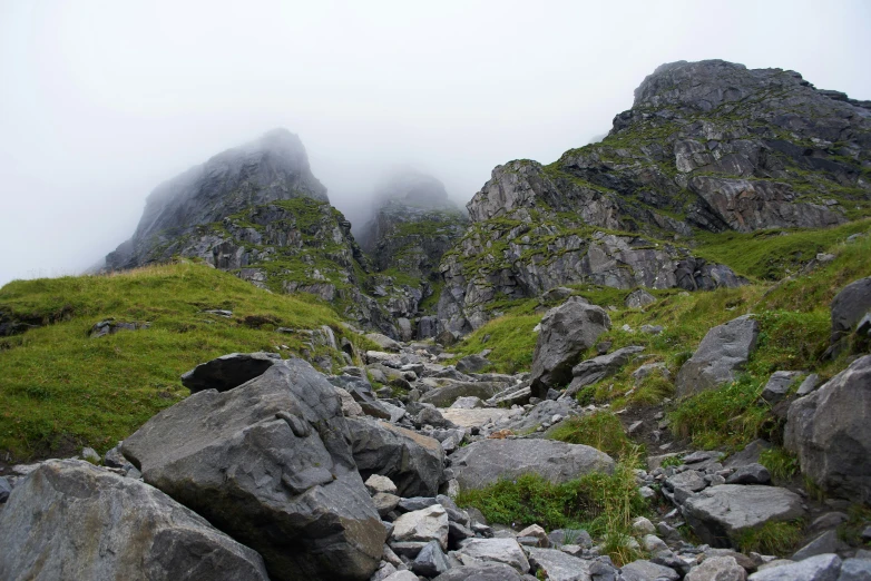 some rocks bushes grass and clouds on a mountain