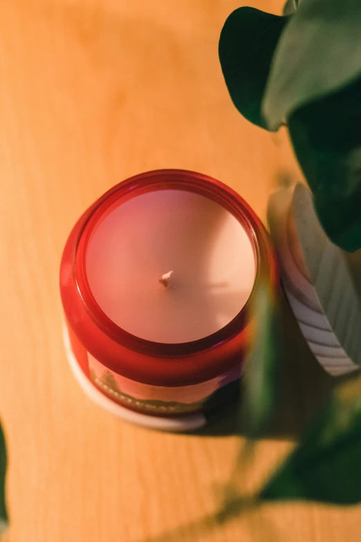 candle in red glass container sitting on a table