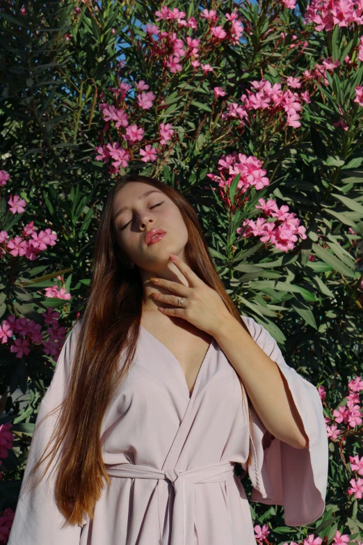 young woman posing for the camera in front of pink flowers