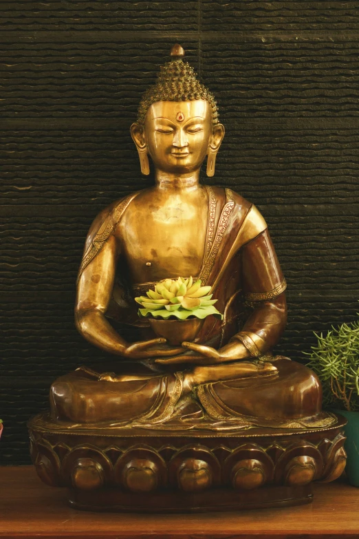 a golden buddha statue sitting on top of a wooden table