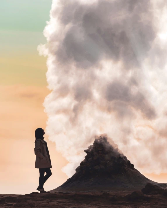 woman standing at the bottom of a mountain staring off into the sky