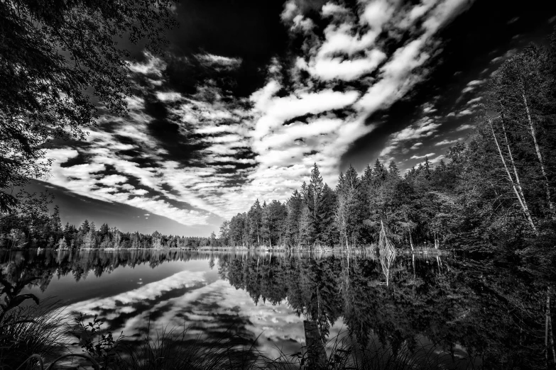 clouds and trees are reflected in the water