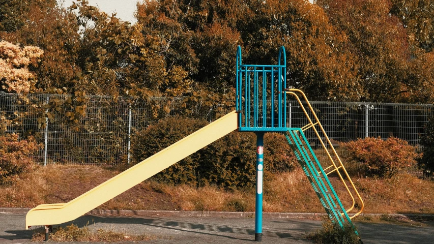 a play area with swings, climbing bars and shrubbery in the background