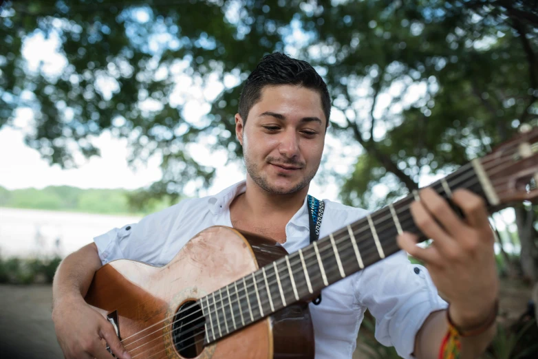 a man is playing a guitar under some trees