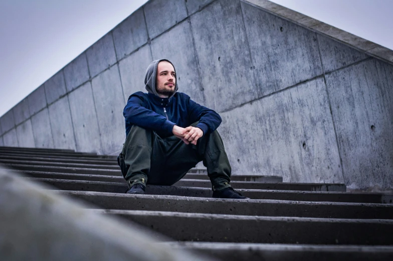 a man in a blue jacket sitting on some steps