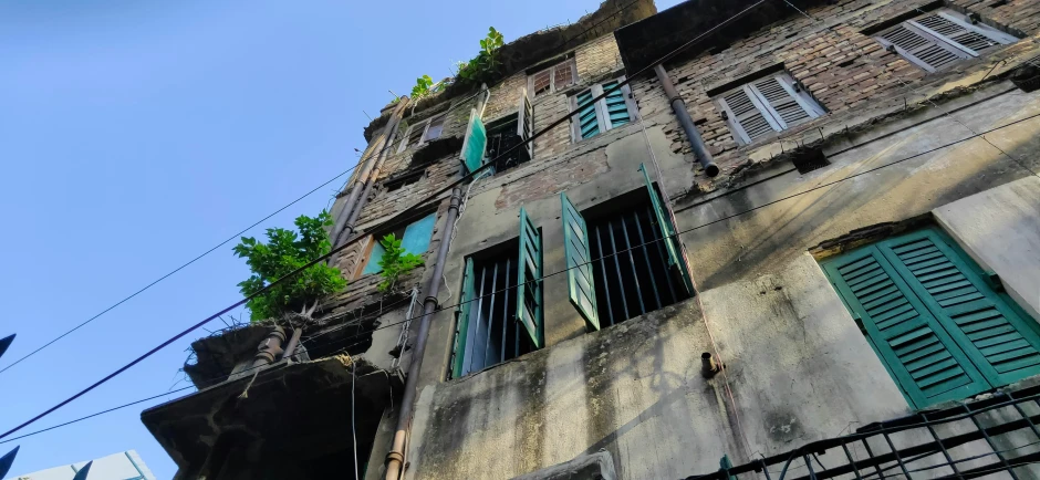 a rundown apartment building with green shutters on its windows