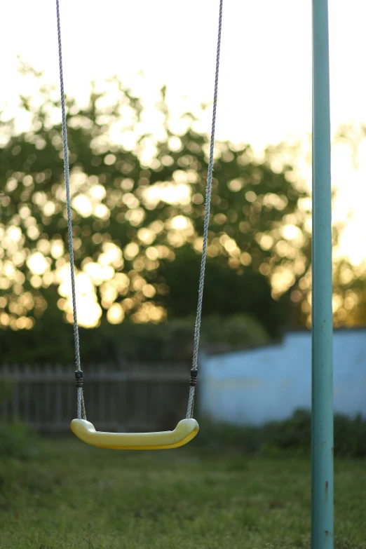 the yellow plastic swing is attached to a pole