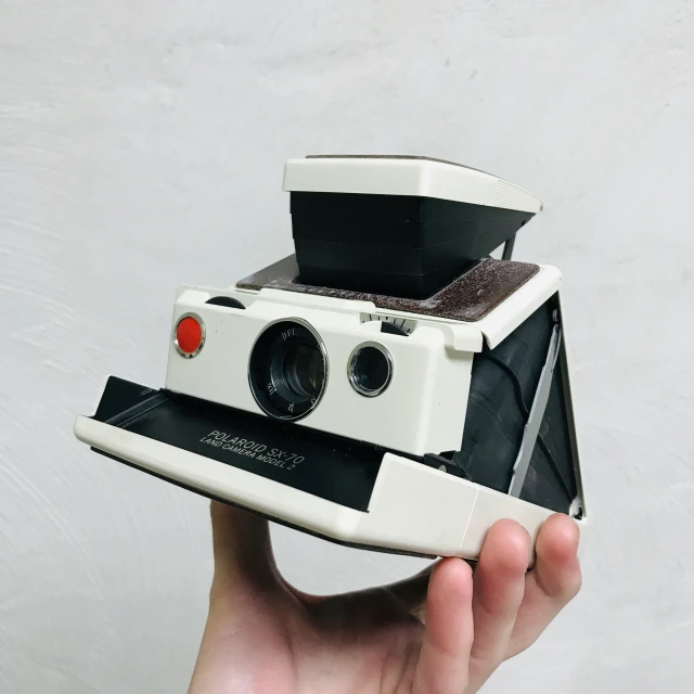 a polaroid camera is held in the palm of a hand