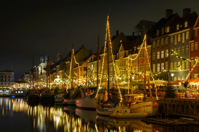 boats are parked next to a row of buildings with christmas lights on