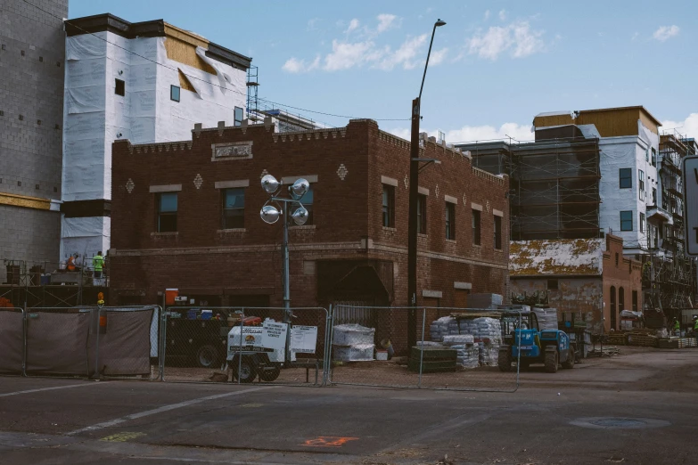 an old brick building is behind the fence of a construction site