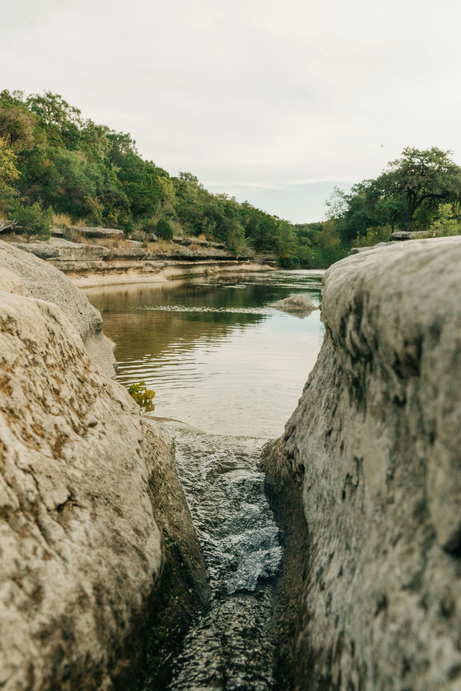 a stream that runs through between rocks into a river