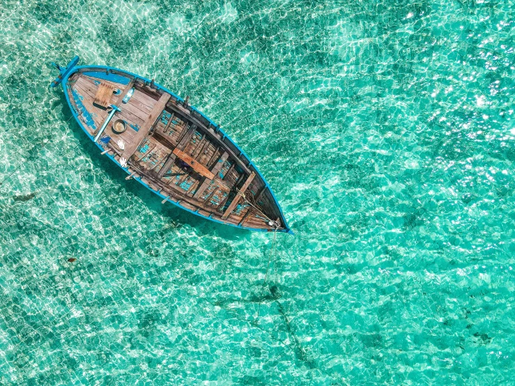 an aerial view of a small blue and brown boat in the blue water