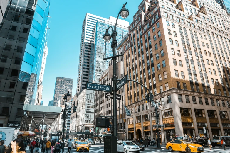 the street has many cars and pedestrians along with tall buildings