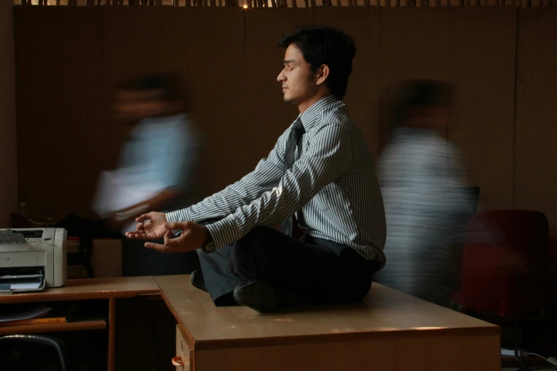 the man is meditating while sitting on a desk