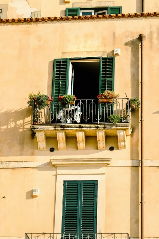 the front of a building with a balcony and green shutters