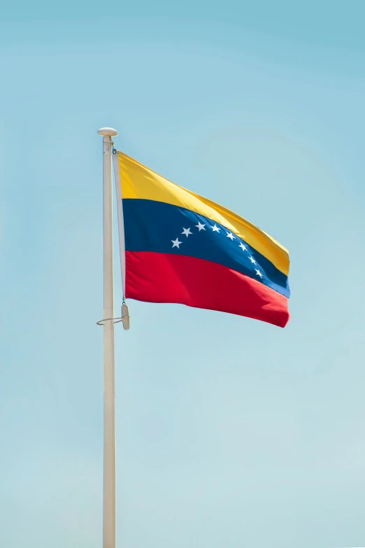the flag of venezuela flying in a blue sky