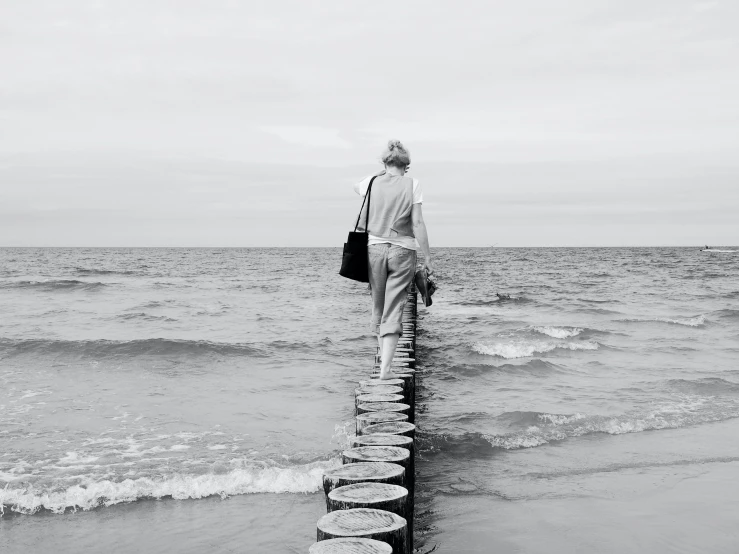 there is a man standing on a pier at the beach