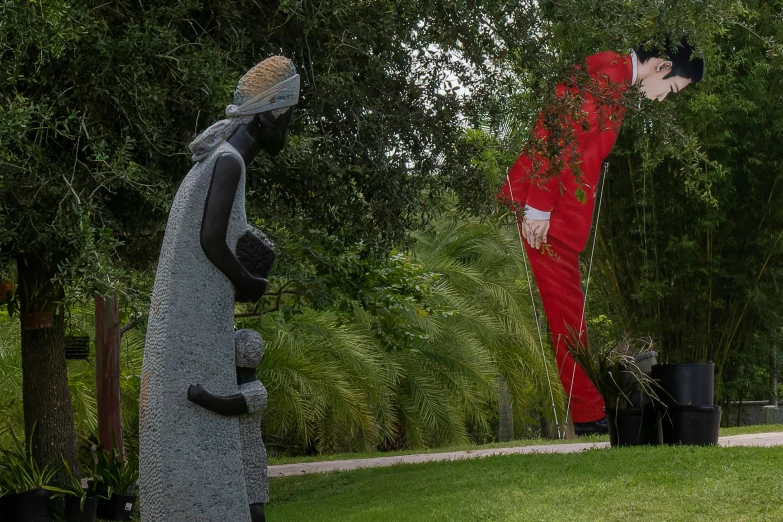 statue of two people with an alien looking face on a lawn