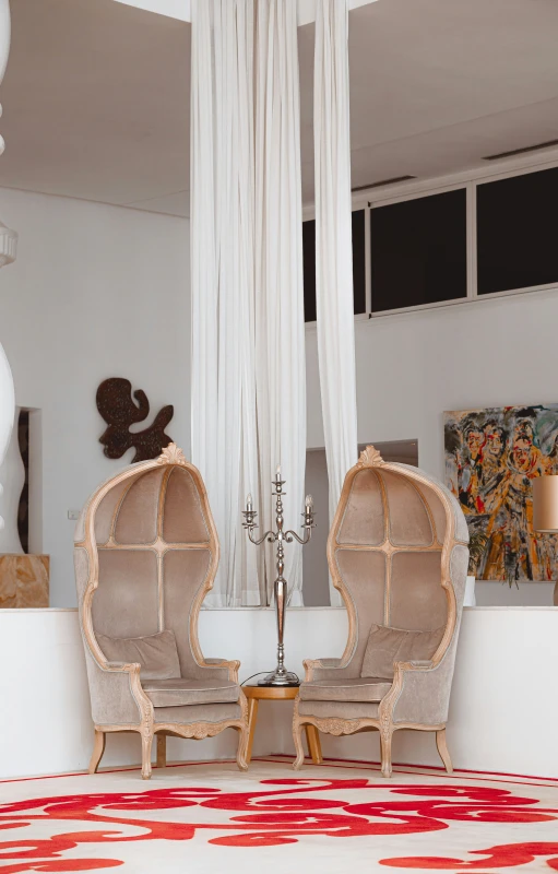 two chairs sitting on a red rug in front of white curtains