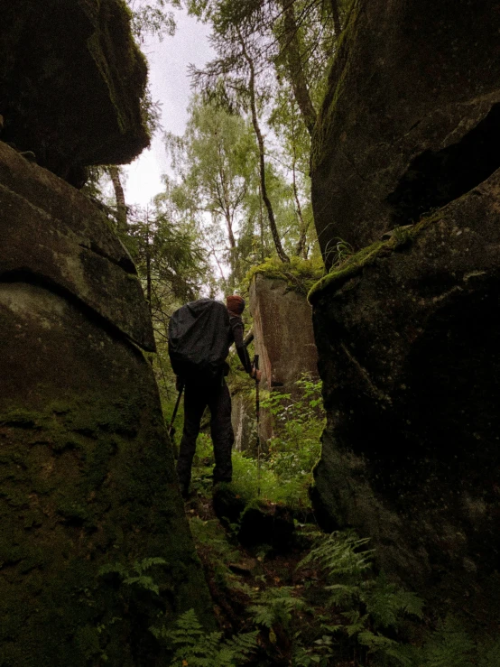 a man walking along between two large rocks in a forest