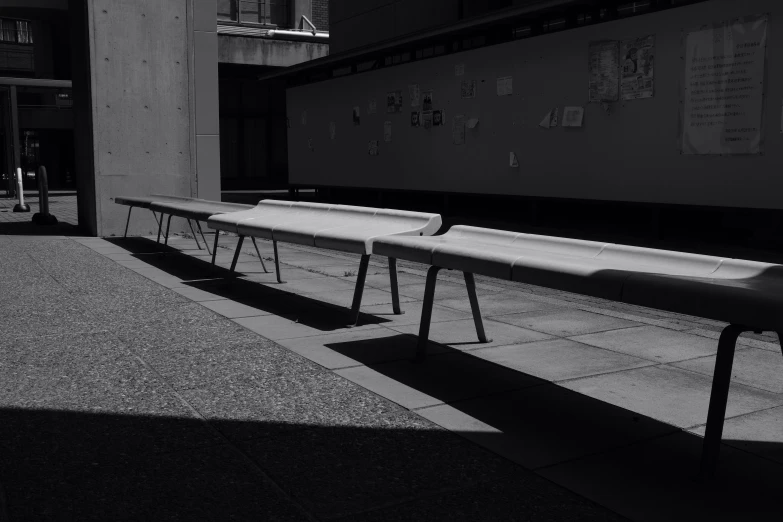 two white benches line up near a building