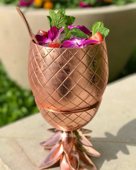 a copper colored cocktail shaker with strawberries in the middle