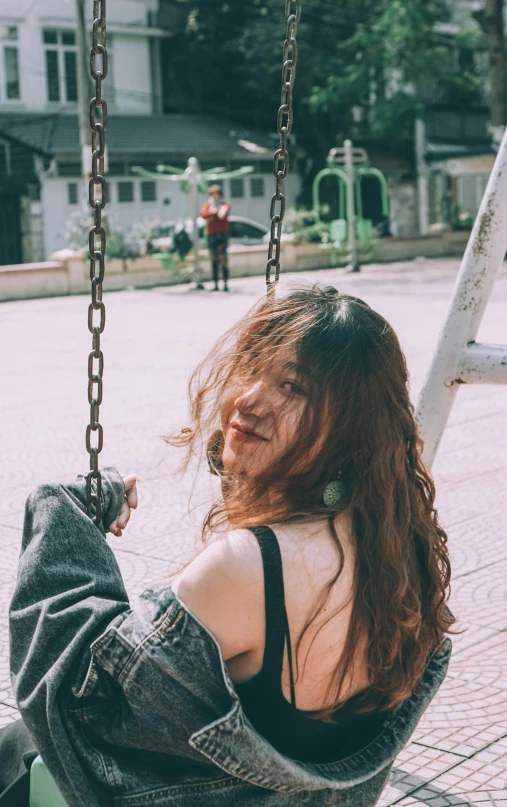 a woman is sitting on a swing outside