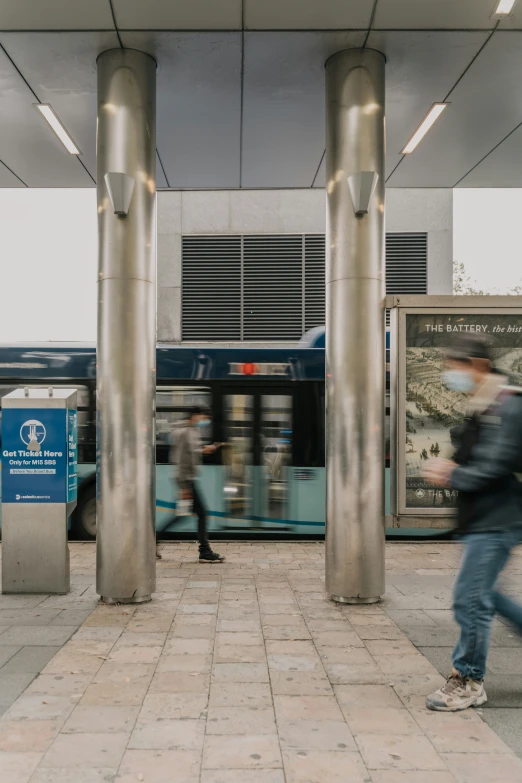 a man is walking near two large silver pillars