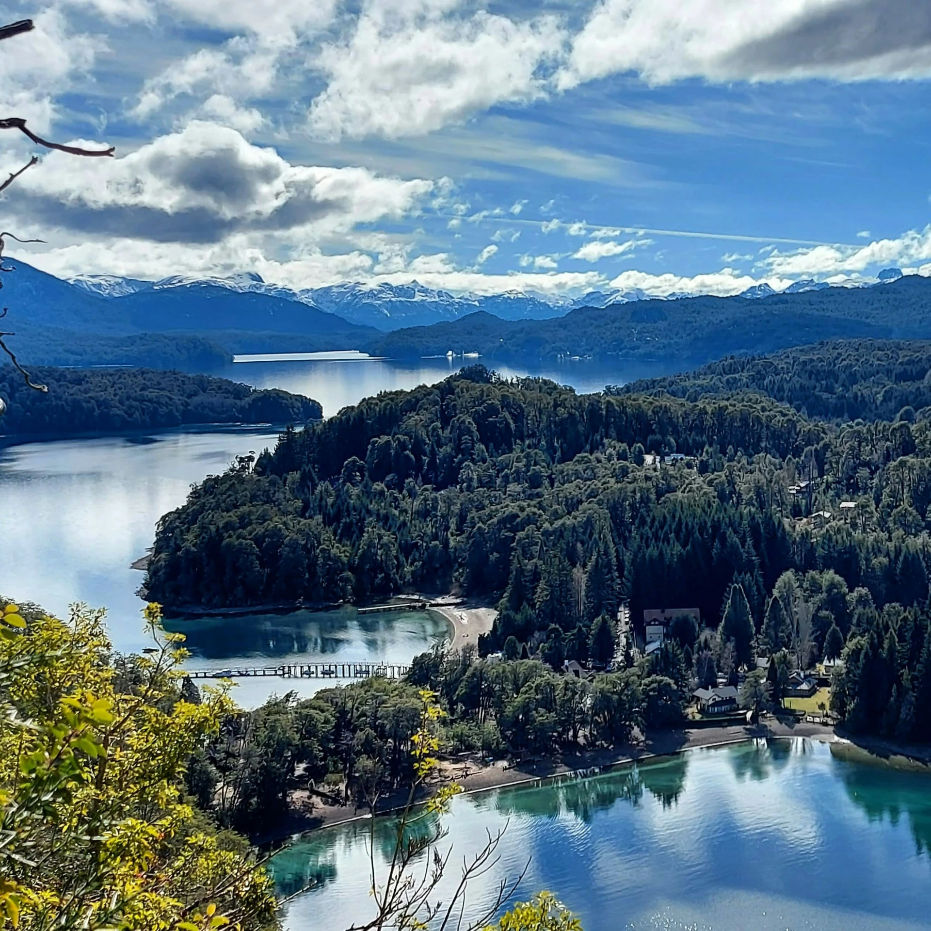 a view of a lake surrounded by mountains with trees and snow