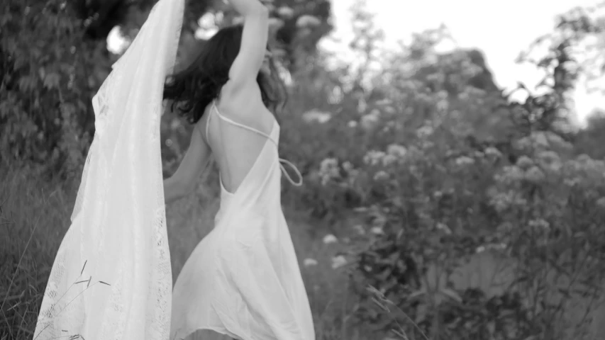 a woman in white dress holding a veil over her head