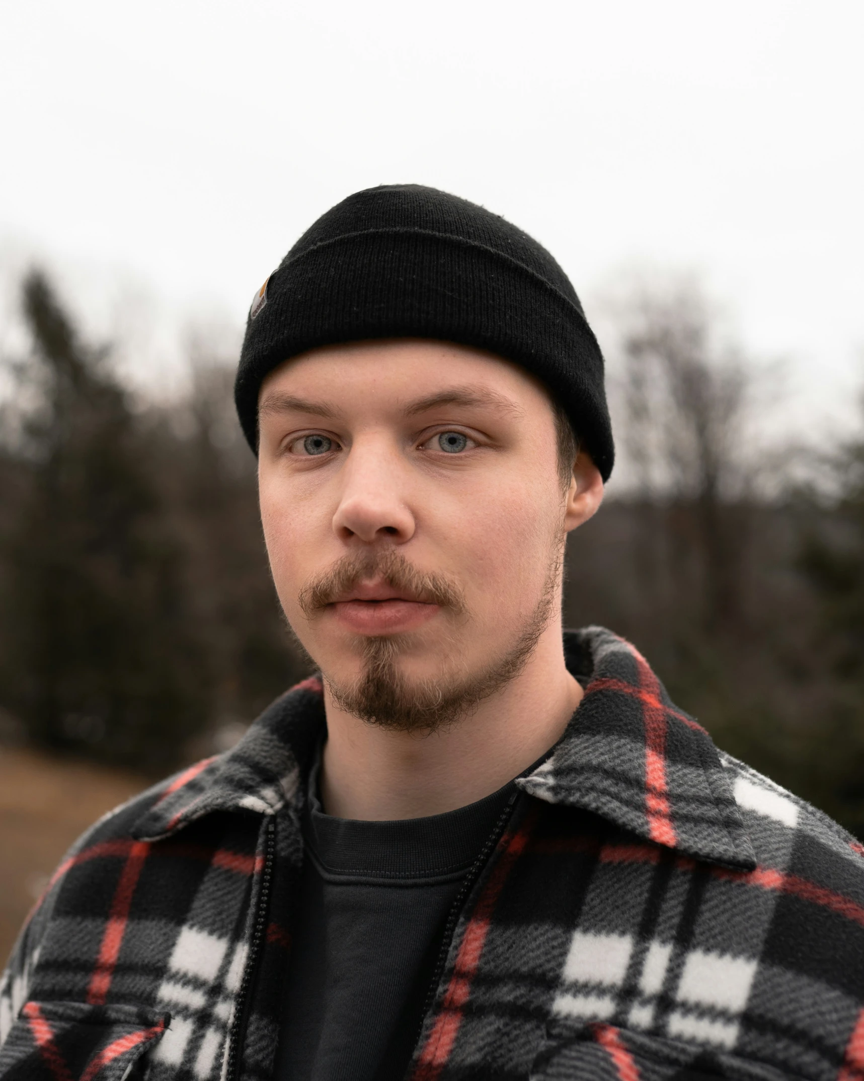 a man with a beard and a cap is wearing a jacket