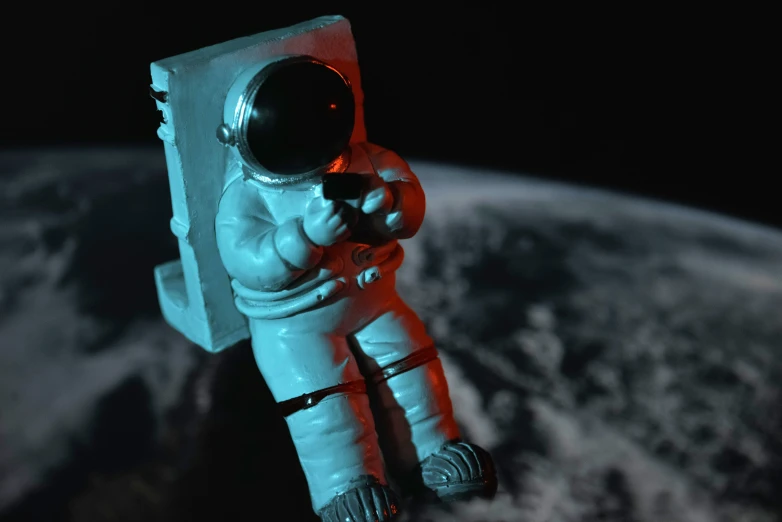 a small statue of an astronaut on the surface of earth