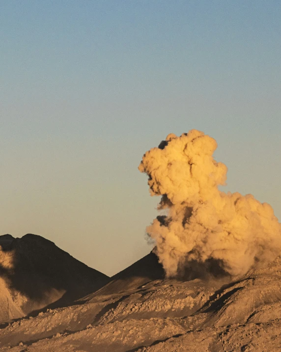 smoke billowing out from top of a mountain against blue sky