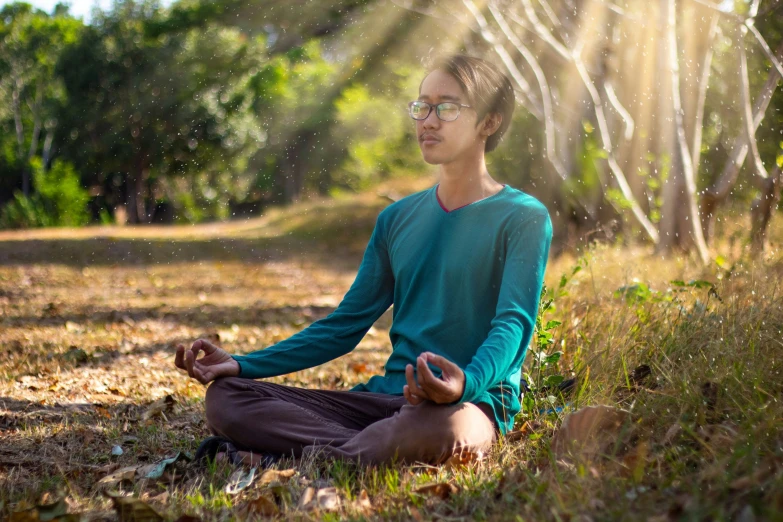 a man is sitting in the grass meditating