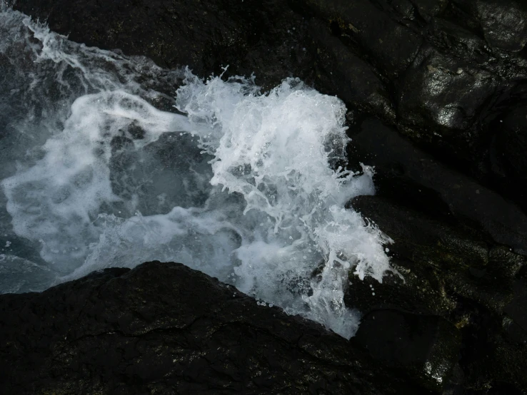 the white foamy water of the ocean sprays upon rocks