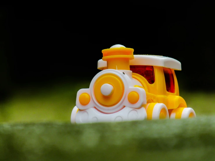 a toy train with orange wheels on green grass