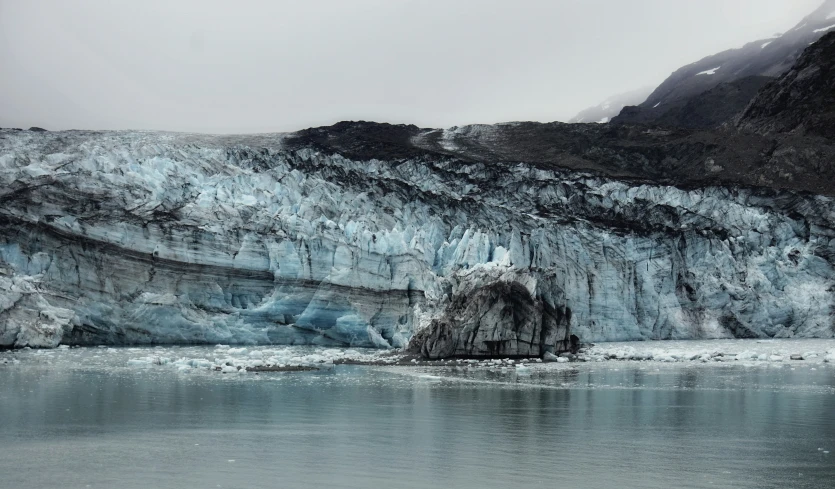 an ice mountain with water, snow, and rock formations