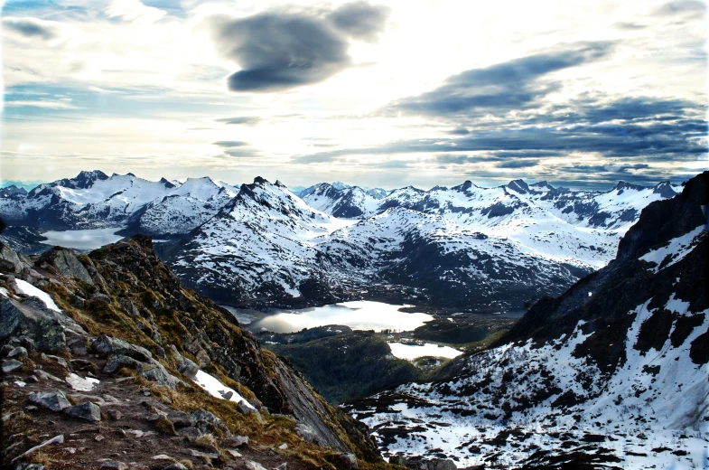 an incredible view shows high mountains, snow - covered cliffs, and a lake