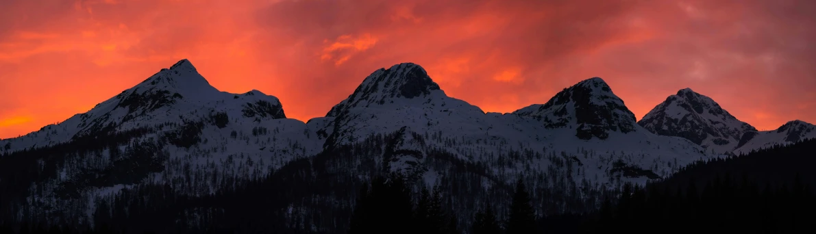 a sunset sky behind snow covered mountains